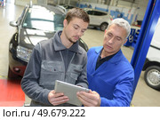 auto mechanic teacher and trainee performing tests at mechanic school. Стоковое фото, агентство Ingram Publishing / Фотобанк Лори