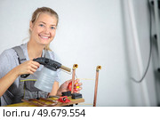 happy woman soldering cooper pipes. Стоковое фото, агентство Ingram Publishing / Фотобанк Лори