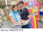 happy couple looking at outfits magazine in a costume shop. Стоковое фото, агентство Ingram Publishing / Фотобанк Лори