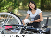 woman applying bandage to knee after falling from bicycle. Стоковое фото, агентство Ingram Publishing / Фотобанк Лори