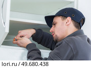a man installing a fitted cupboard. Стоковое фото, агентство Ingram Publishing / Фотобанк Лори