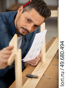man assembles wooden furniture following instructions. Стоковое фото, агентство Ingram Publishing / Фотобанк Лори