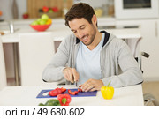 handsome man in wheelchair cuts veggetables. Стоковое фото, агентство Ingram Publishing / Фотобанк Лори