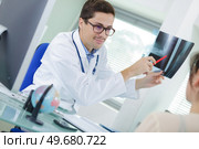 doctor explaining spine x-ray to patient in office. Стоковое фото, агентство Ingram Publishing / Фотобанк Лори