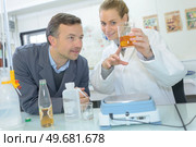laboratory technician mixing liquids in lab while assistant write data. Стоковое фото, агентство Ingram Publishing / Фотобанк Лори