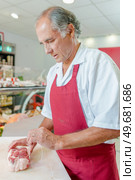 a butcher is preparing meat. Стоковое фото, агентство Ingram Publishing / Фотобанк Лори