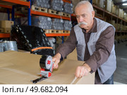 senior worker taping a box in warehouse. Стоковое фото, агентство Ingram Publishing / Фотобанк Лори