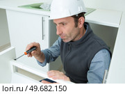 workman installing a fitted kitchen. Стоковое фото, агентство Ingram Publishing / Фотобанк Лори