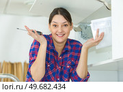 woman making clueless hand gesture while fitting kitchen cupboard. Стоковое фото, агентство Ingram Publishing / Фотобанк Лори