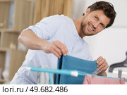 man airing laundry indoors. Стоковое фото, агентство Ingram Publishing / Фотобанк Лори