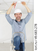 man using screwdriver to install smoke detector on ceiling. Стоковое фото, агентство Ingram Publishing / Фотобанк Лори