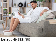 man on the sofa soaking his feet. Стоковое фото, агентство Ingram Publishing / Фотобанк Лори