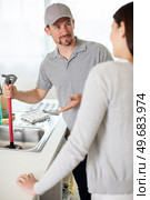 woman looking at male plumber cleaning clogged sink. Стоковое фото, агентство Ingram Publishing / Фотобанк Лори