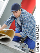 close up of male worker unrolling carpet in office. Стоковое фото, агентство Ingram Publishing / Фотобанк Лори