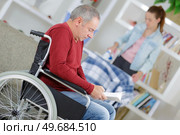 daughter helping father in wheelchair at home. Стоковое фото, агентство Ingram Publishing / Фотобанк Лори