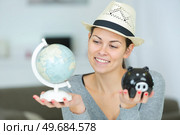 woman holding globe and piggy bank wearing sunhat. Стоковое фото, агентство Ingram Publishing / Фотобанк Лори