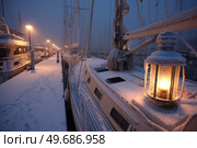 A boat is docked at a marina with a lantern lit on the deck. Стоковое AI-изображение, AI-художник Ярославский Максим / Фотобанк Лори