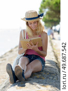 woman reading book on a seawall. Стоковое фото, агентство Ingram Publishing / Фотобанк Лори