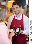 sommelier in wine store giving woman recommendation for wine. Стоковое фото, агентство Ingram Publishing / Фотобанк Лори