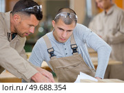 workman and apprentice looking at plans. Стоковое фото, агентство Ingram Publishing / Фотобанк Лори