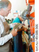 Cobbler grinding heel of shoe. Стоковое фото, агентство Ingram Publishing / Фотобанк Лори