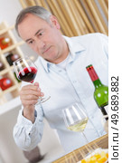 elderly man looking at a red wine in the glass. Стоковое фото, агентство Ingram Publishing / Фотобанк Лори