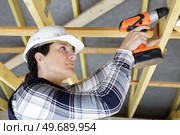female builder using cordless drill overhead. Стоковое фото, агентство Ingram Publishing / Фотобанк Лори