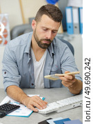 satisfied man standing checking a brush in computer. Стоковое фото, агентство Ingram Publishing / Фотобанк Лори