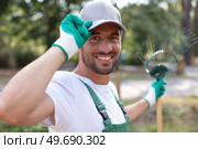 male gardener with rake touching his cap in greeting. Стоковое фото, агентство Ingram Publishing / Фотобанк Лори
