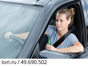young lady driver is drinking beer while she is driving. Стоковое фото, агентство Ingram Publishing / Фотобанк Лори