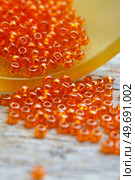 orange  small beads around old style wooden background. macro shot. hobby and hand made concept. Стоковое фото, агентство Ingram Publishing / Фотобанк Лори