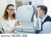 female optometrist examining male patient on phoropter. Стоковое фото, агентство Ingram Publishing / Фотобанк Лори