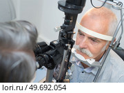 senior man looking into slit lamp at clinic. Стоковое фото, агентство Ingram Publishing / Фотобанк Лори