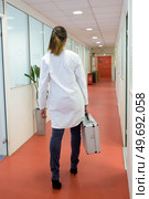 rear view of woman in labcoat carrying a metal case. Стоковое фото, агентство Ingram Publishing / Фотобанк Лори