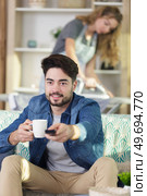 woman ironing clothes and man watching tv. Стоковое фото, агентство Ingram Publishing / Фотобанк Лори