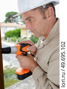man drills a wooden board with a drill. Стоковое фото, агентство Ingram Publishing / Фотобанк Лори