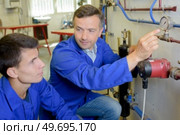 technician and apprentice working with gauge. Стоковое фото, агентство Ingram Publishing / Фотобанк Лори