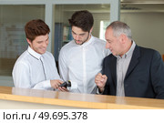 two teen men and their teacher during their receptionist training. Стоковое фото, агентство Ingram Publishing / Фотобанк Лори