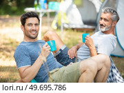 two men relaxing and having a drink by their tents. Стоковое фото, агентство Ingram Publishing / Фотобанк Лори