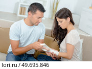 boyfriend helping girlfriend with fractured hand sitting on sofa. Стоковое фото, агентство Ingram Publishing / Фотобанк Лори