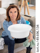 disgruntled older woman catching leaking water in a bowl. Стоковое фото, агентство Ingram Publishing / Фотобанк Лори