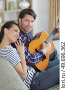 woman enjoying the tune her boyfriend plays on the guitar. Стоковое фото, агентство Ingram Publishing / Фотобанк Лори