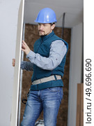 construction worker in overalls uniform picking up a drywall sheet. Стоковое фото, агентство Ingram Publishing / Фотобанк Лори