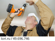 man is drilling holes into concrete ceiling with drilling machine. Стоковое фото, агентство Ingram Publishing / Фотобанк Лори