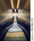 Lone man climbing out on a subway escalator. Symmetrical underground moving staircase. Стоковое фото, агентство Ingram Publishing / Фотобанк Лори