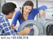 repairman repairing washer in front of woman. Стоковое фото, агентство Ingram Publishing / Фотобанк Лори