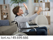 happy crippled man holding a tablet and waving. Стоковое фото, агентство Ingram Publishing / Фотобанк Лори