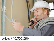 electrician technician looking at electric cable. Стоковое фото, агентство Ingram Publishing / Фотобанк Лори