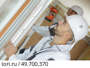 workmen fitting a window at a construction site. Стоковое фото, агентство Ingram Publishing / Фотобанк Лори