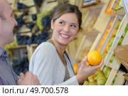 Smiling shop assistant holding orange. Стоковое фото, агентство Ingram Publishing / Фотобанк Лори